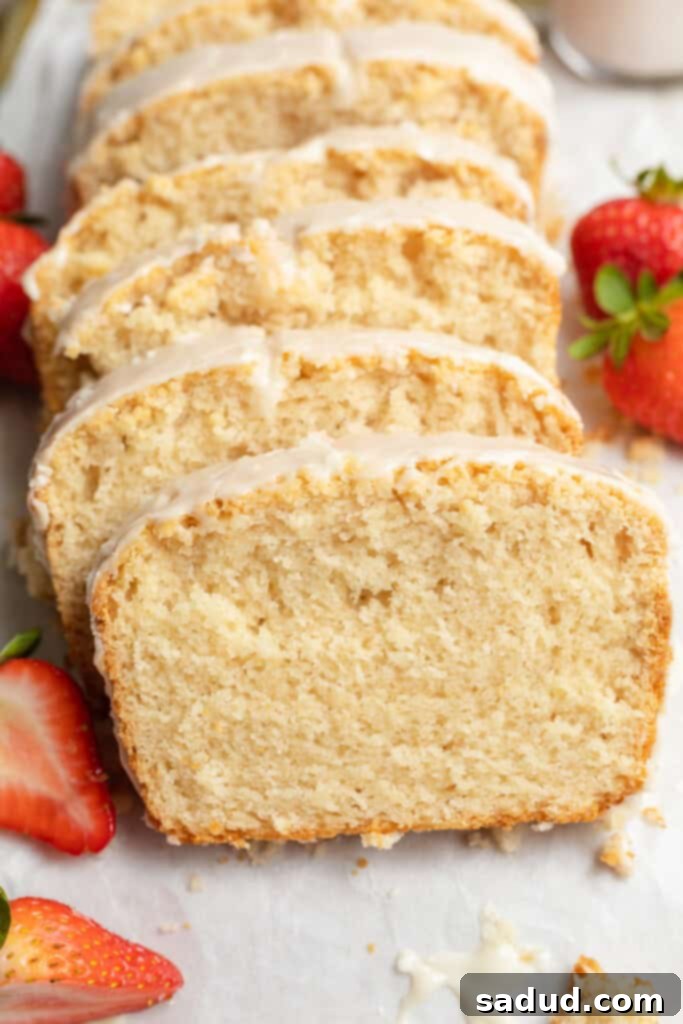 close up image of sliced vegan pound cake with strawberries on the side