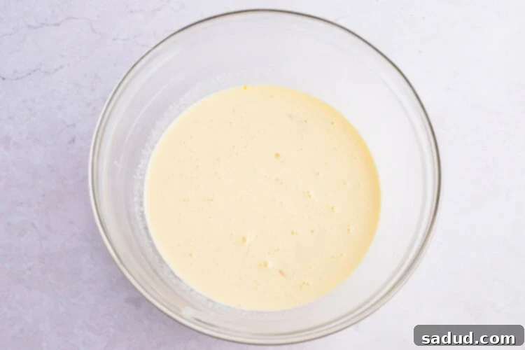 Keto pudding mixture in a large glass bowl, ready to be poured over the bread.