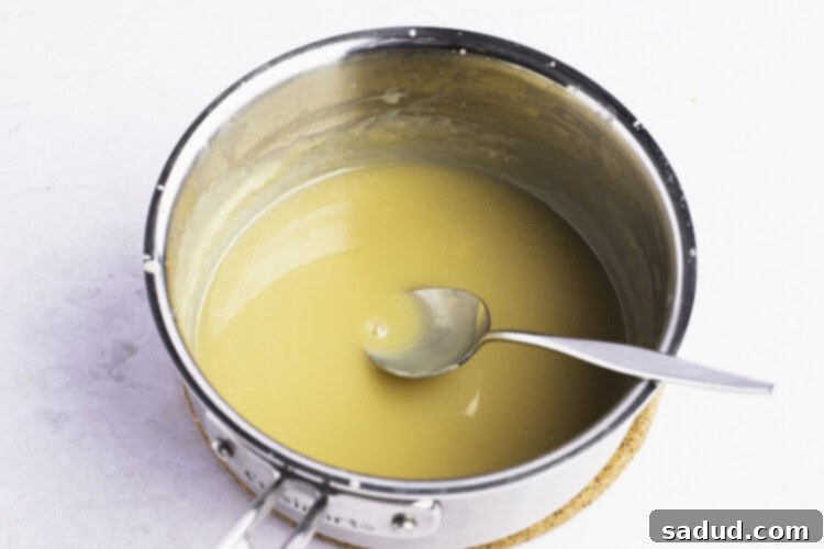 Keto vanilla sauce simmering in a small saucepan, thickening to perfection.