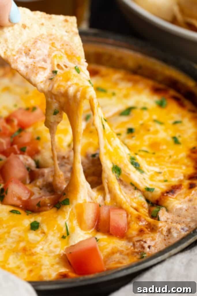 chili cheese dip being scooped up by a chip
