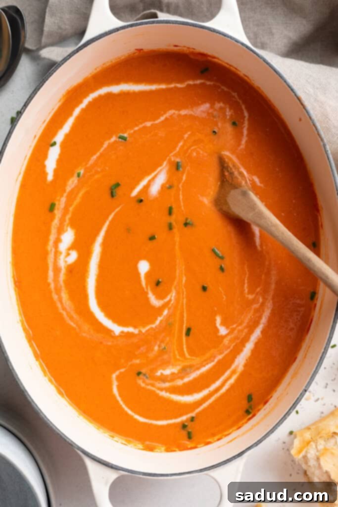 gluten free tomato soup in a large pot with heavy cream swirled on top