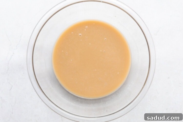 Butter, almond milk, white sugar, and brown sugar mixed together in large glass mixing bowl.