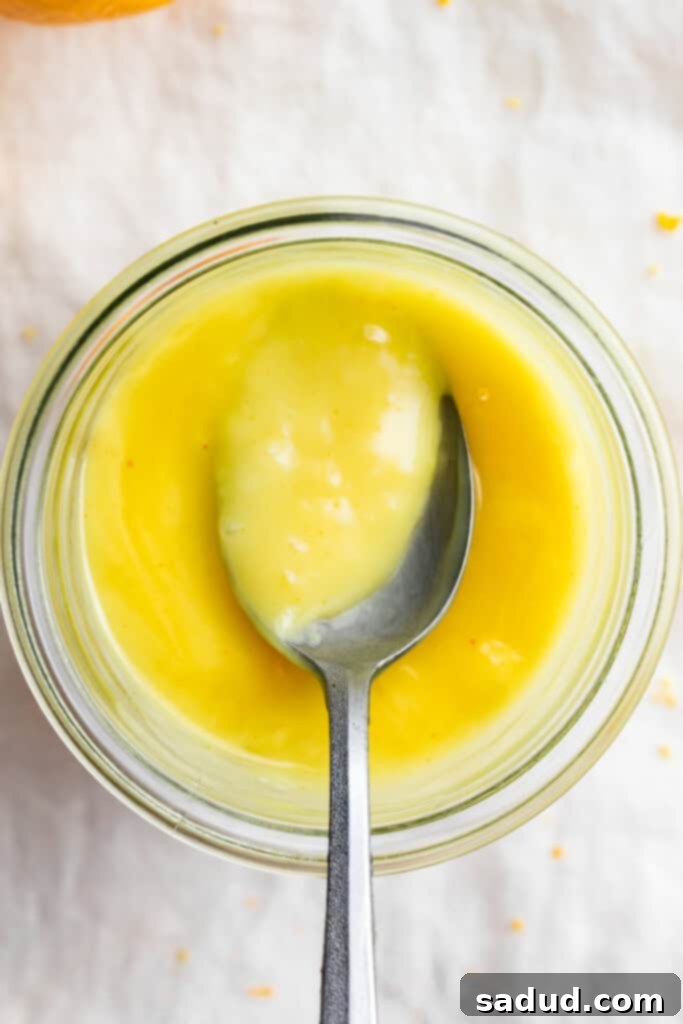 Overhead view of a jar of vegan lemon curd with a spoon.