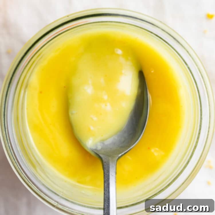 Overhead view of a jar of vegan lemon curd with a spoon.