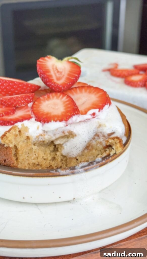 Gluten-free, paleo Strawberry shortcake mug cake with whipped cream and fresh strawberries. Close-up of texture.