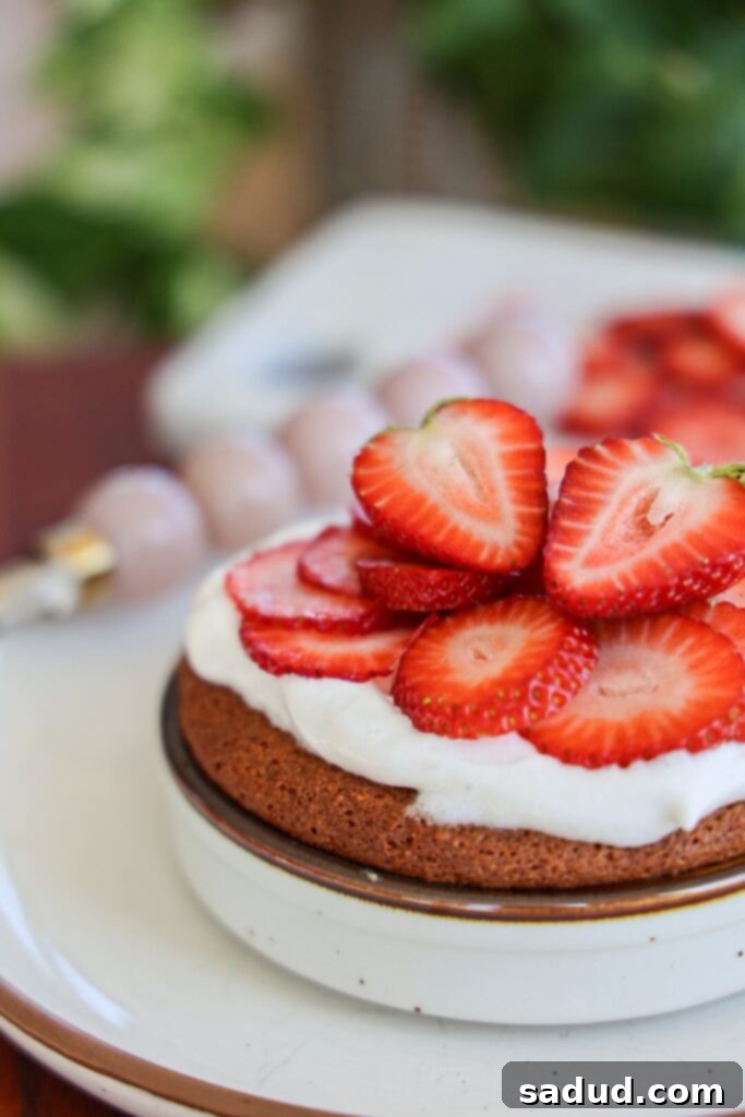 Healthy Strawberry shortcake mug cake ready to be served, topped with berries and cream.