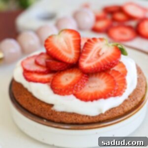 Healthy Strawberry Shortcake Mug Cake with coconut whipped topping and fresh berries, served in a ramekin.