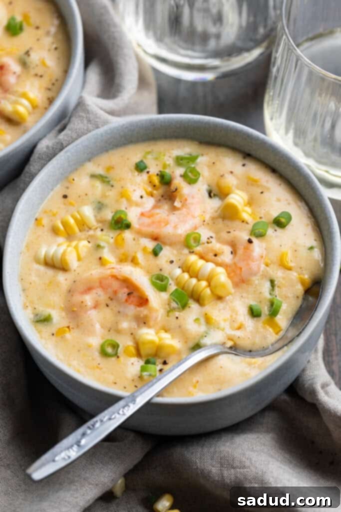 Close-up, 3/4 angle view of a bowl of rich, creamy shrimp and corn soup with fresh garnishes, ready to be enjoyed as a comforting meal.