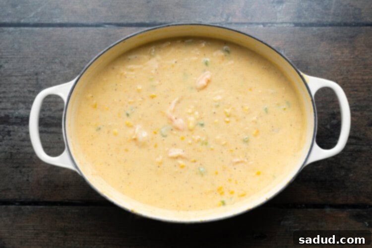 Overhead view of a large soup pot with shrimp and corn soup, perfectly seasoned with Old Bay, nearly ready to serve, showcasing the tender shrimp and vibrant corn.