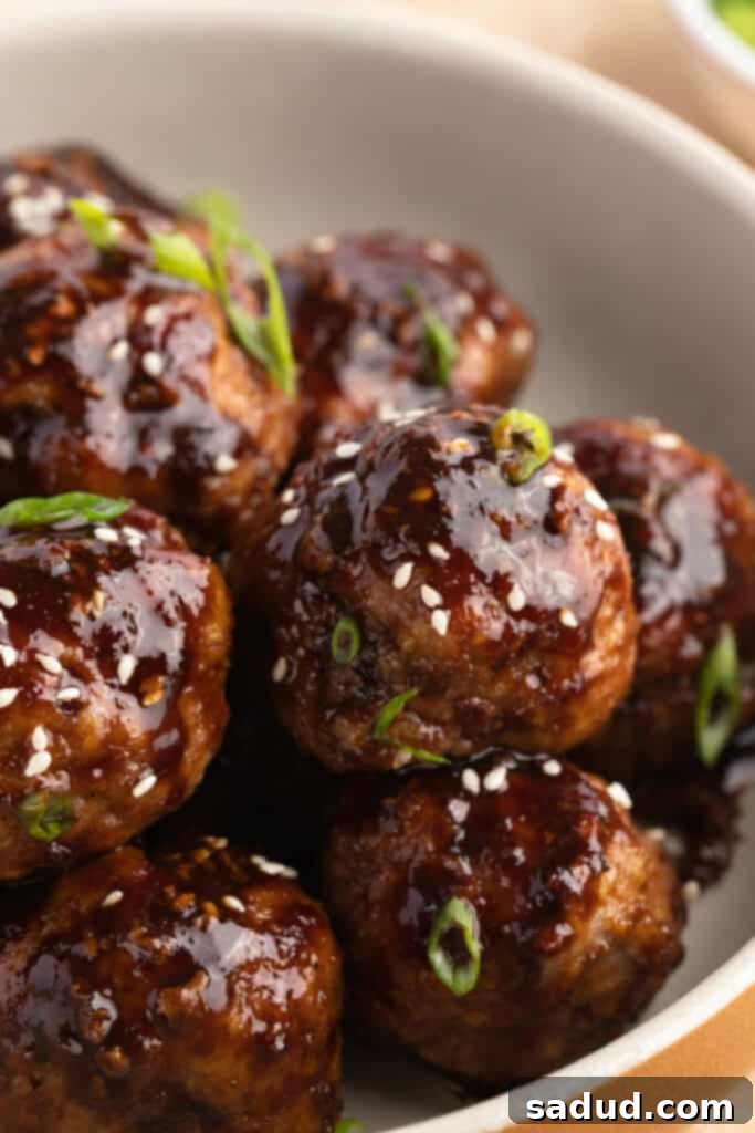 Soy-Ginger Glazed Turkey Bites 3 Close-up view of a bowl of Asian turkey meatballs garnished with toasted sesame seeds and thinly sliced green onions.