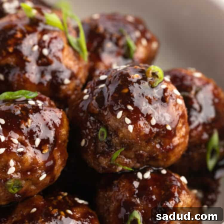 Soy-Ginger Glazed Turkey Bites 4 Close-up view of a bowl of Asian turkey meatballs garnished with sesame seeds and green onions.