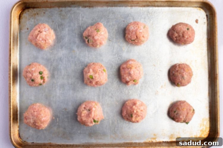 Overhead view of Asian turkey meatballs on a lightly greased baking sheet.