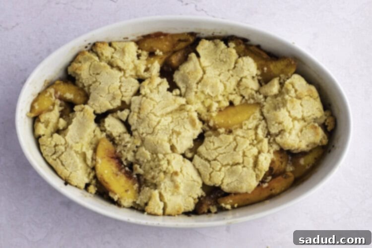 Baked keto peach cobbler in large white oval baking dish.