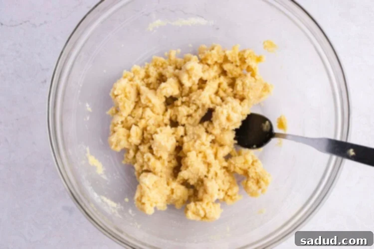 Keto cobbler crust dough in large glass mixing bowl with fork.