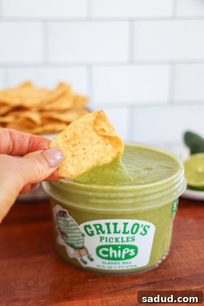 A bowl of dill pickle salsa surrounded by fresh ingredients like cilantro and lime