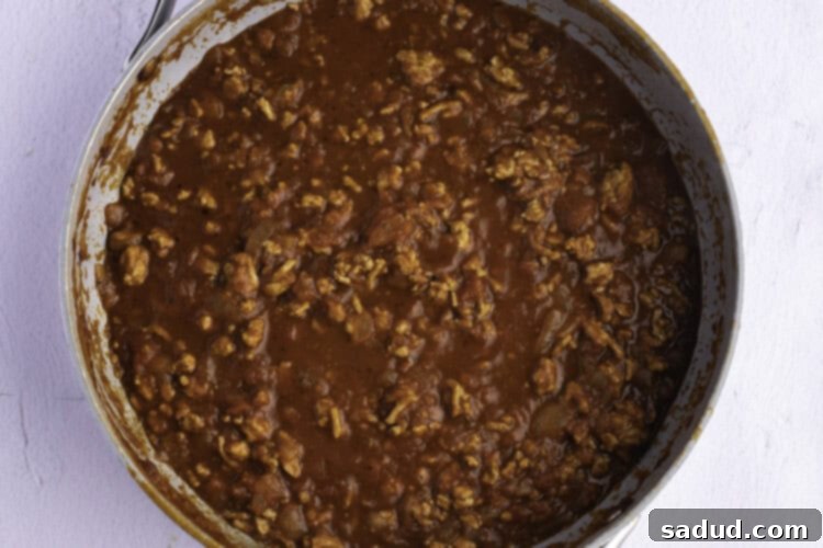 Overhead view of ground turkey and spaghetti sauce in a large skillet on a white background.