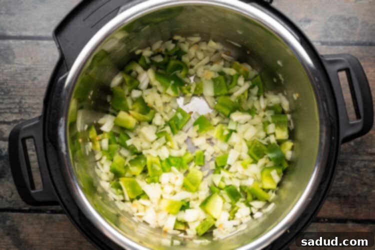 Overhead view of paella ingredients in an Instant Pot, showing sautéed vegetables.