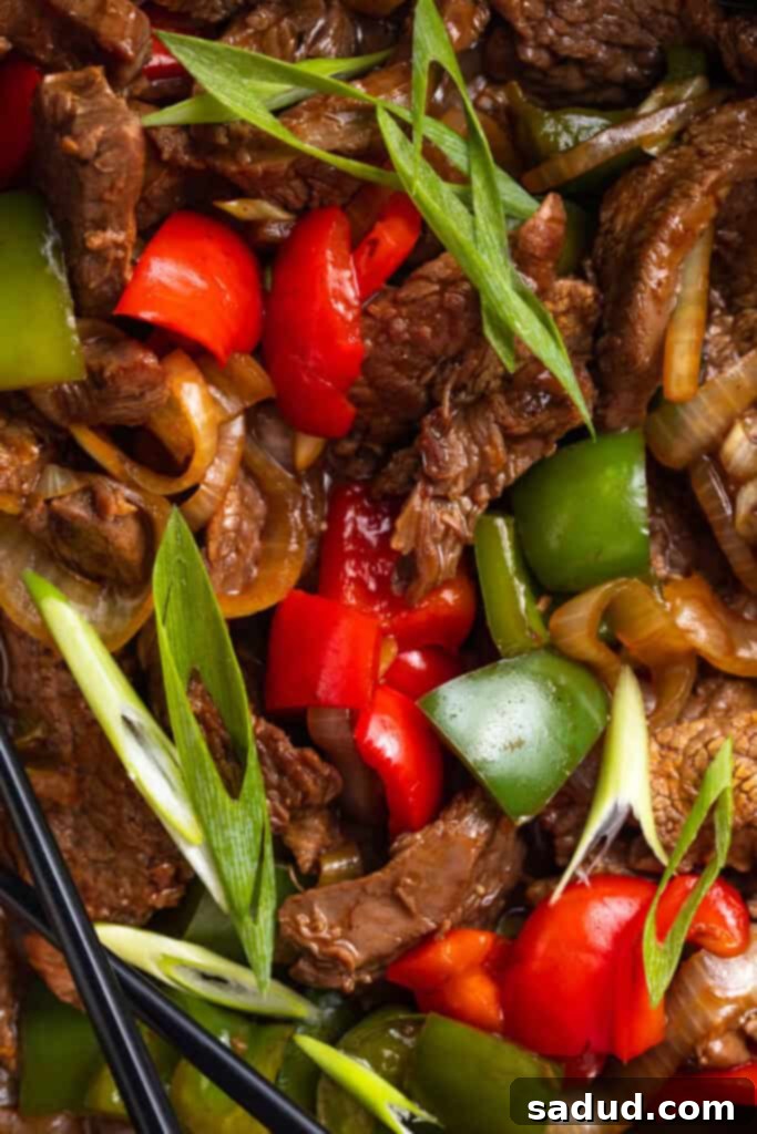 Close-up photo of juicy beef with oyster sauce and colorful stir fry vegetables in a large silver bowl, ready to be served.
