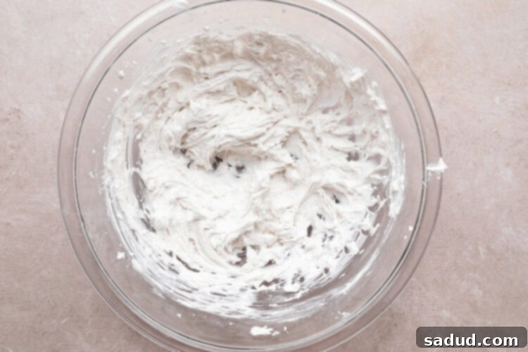 Whipped coconut cream in large glass mixing bowl.