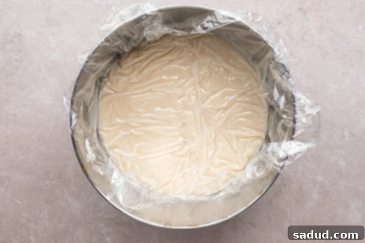 Coconut cream pie filling in large mixing bowl covered with plastic wrap.