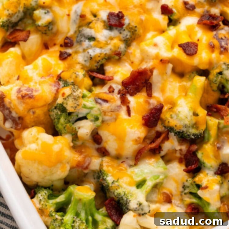 An angled casserole dish, photographed from the corner, holding a keto broccoli cauliflower casserole topped with cheese and bacon pieces.