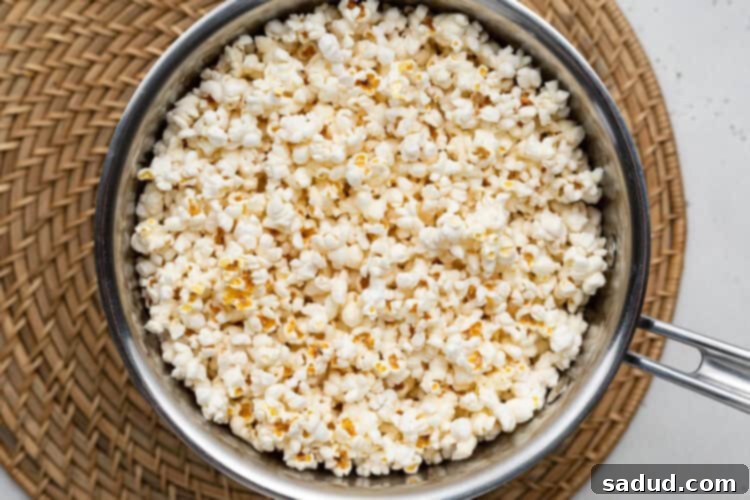 Overhead view of vegan popped popcorn in a large silver pot on a wicker placemat.