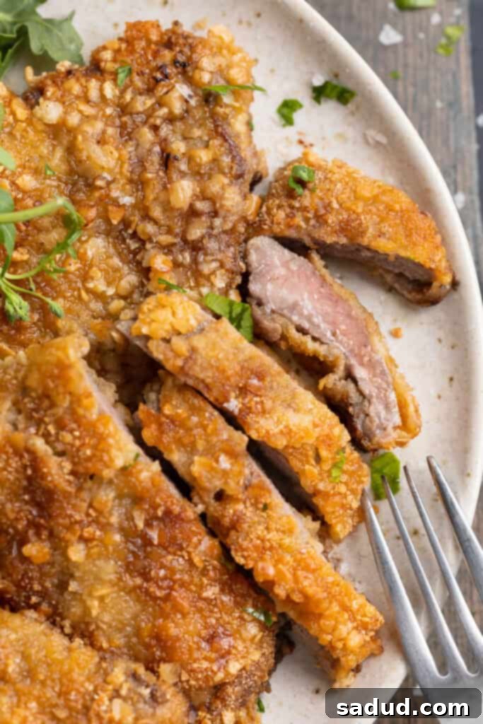 Overhead view of crispy beef schnitzel, sliced thin, with one piece on its side to show the succulent meat and golden crust.