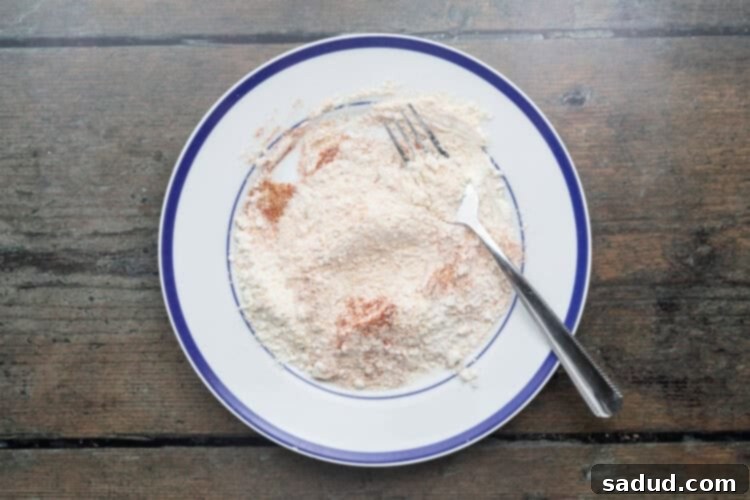 Overhead view of breading mixture for beef schnitzel on a plate with a fork, ready for the first coating step.