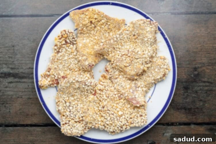 Overhead view of breaded beef schnitzel steaks on a plate, perfectly coated and ready for pan-frying.