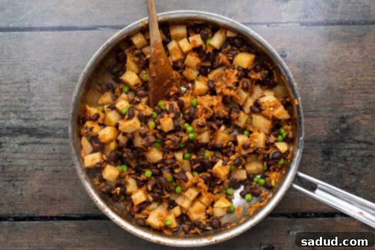 Irresistible Vegan Empanadas 10 Large skillet with empanada filling ingredients on a wooden background.