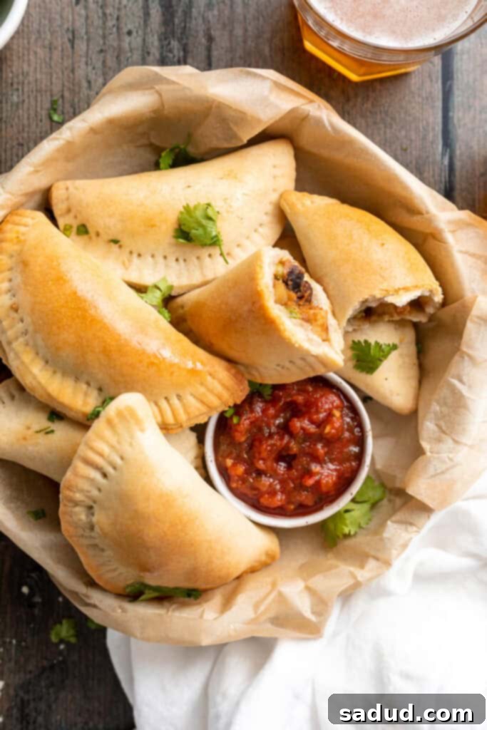 Irresistible Vegan Empanadas 3 Overhead view of a bowl of vegan empanadas next to a small ramekin of red salsa.