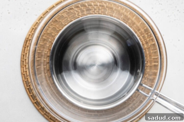 Medium saucepan with large glass bowl sitting on top.