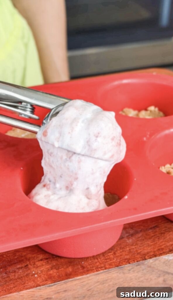 Adding the creamy strawberry topping to the cookie dough base for vegan strawberry shortcake cups.