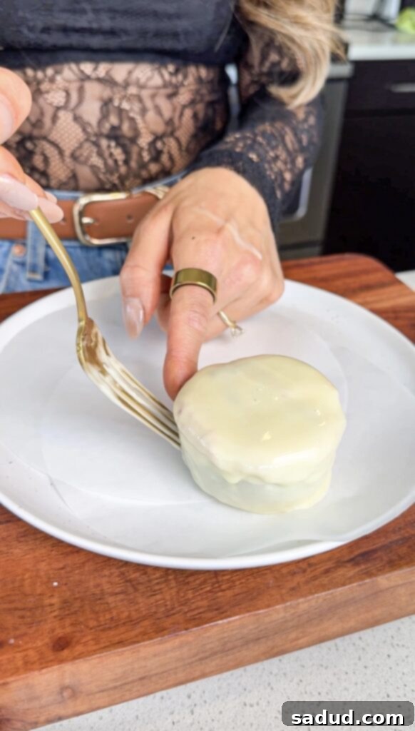 Dipping the frozen strawberry cookie dough cups into melted white chocolate.