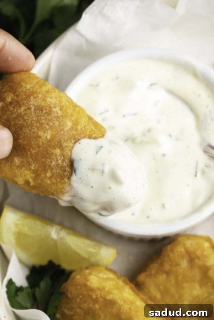 Creamy vegan tartar sauce generously spread over a piece of golden-brown vegan breaded and fried fish, ready to be enjoyed.