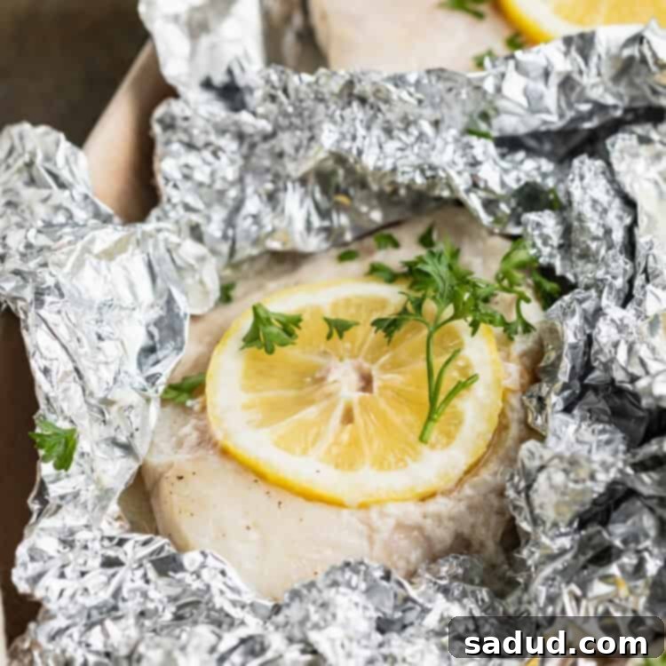 Grilled cod fillet in a foil pouch with lemon discs and fresh herbs.