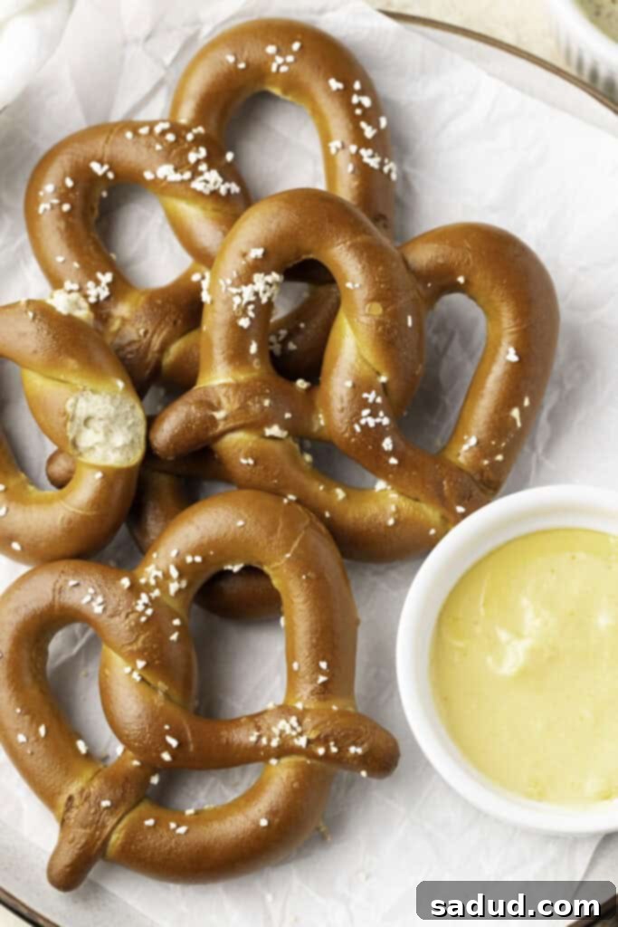 From Freezer to Fantastic: Air Fryer Pretzels 2 4 salted twisted soft pretzels on a white plate next to a ramekin of cheese sauce.