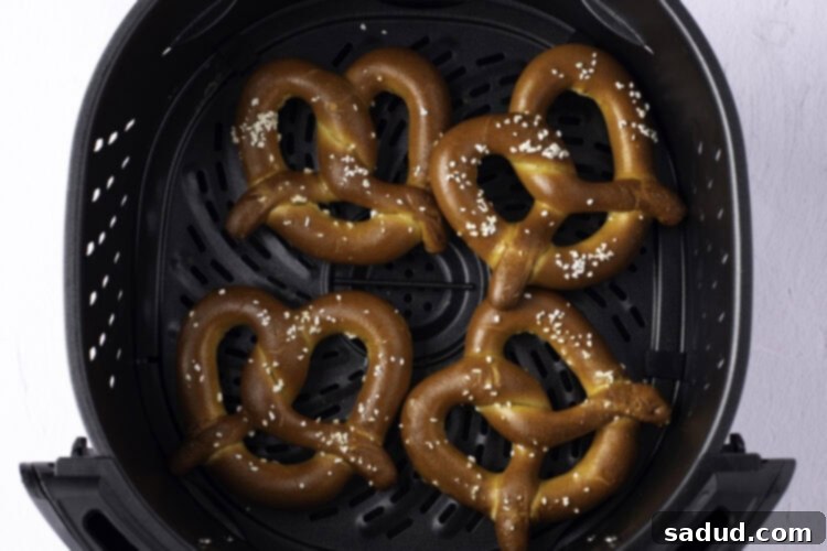 Overhead view of 4 twisted, salted, frozen soft pretzels in the air fryer basket.