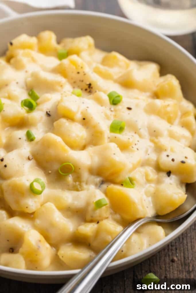 Overhead, angled view of Instant Pot cheesy potatoes in a large neutral bowl with a silver spoon.