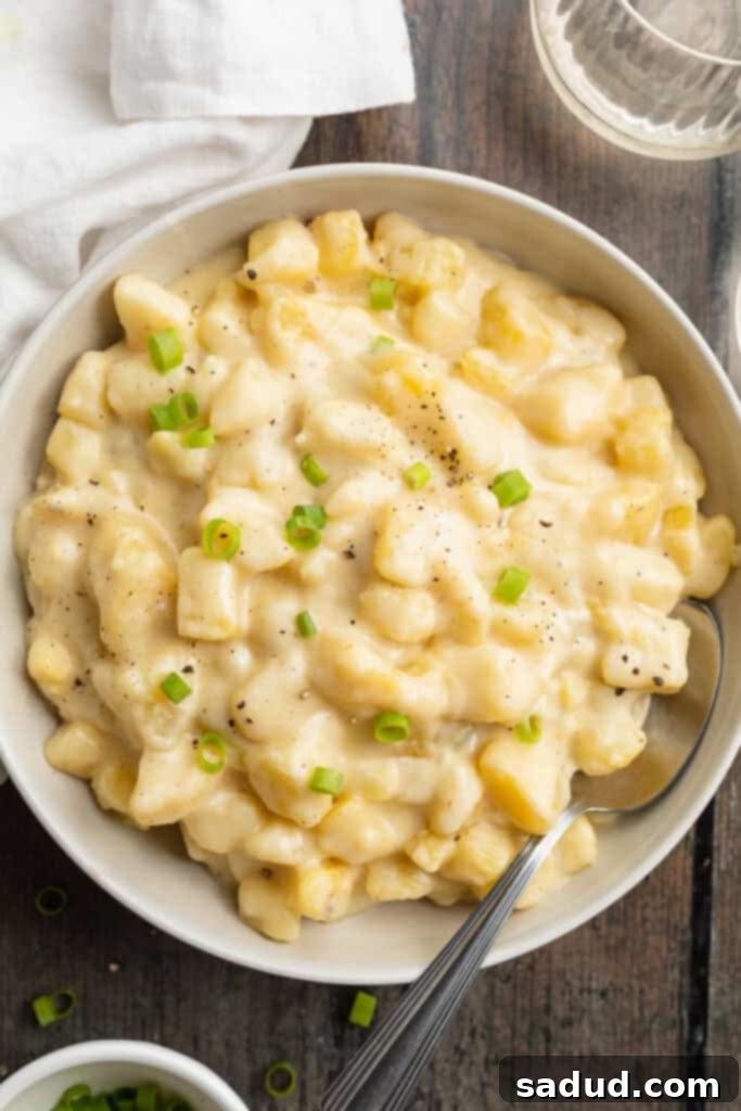 Overhead view of a large bowl of creamy, cheesy Instant Pot potatoes on a wooden table.