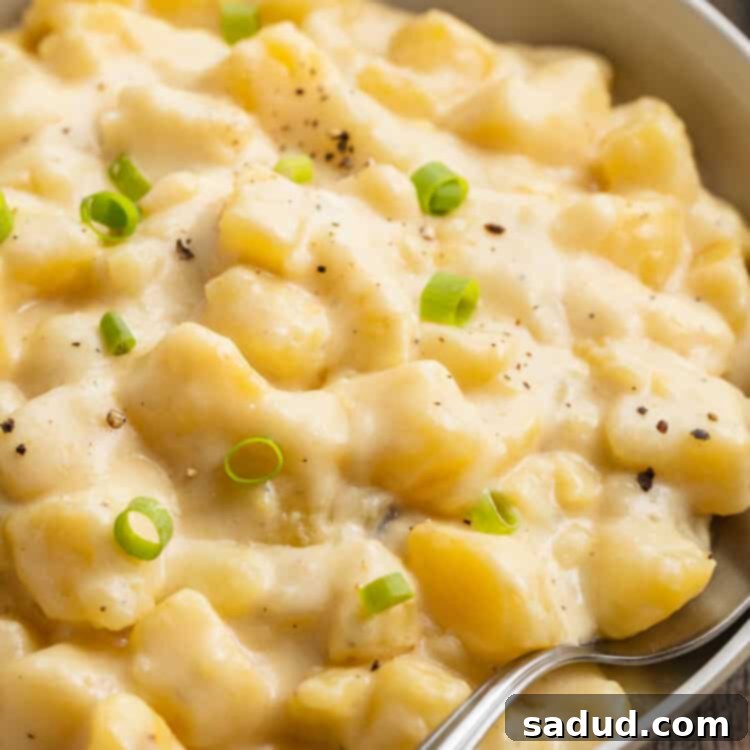 Overhead, angled view of Instant Pot cheesy potatoes in a large neutral bowl with a silver spoon.