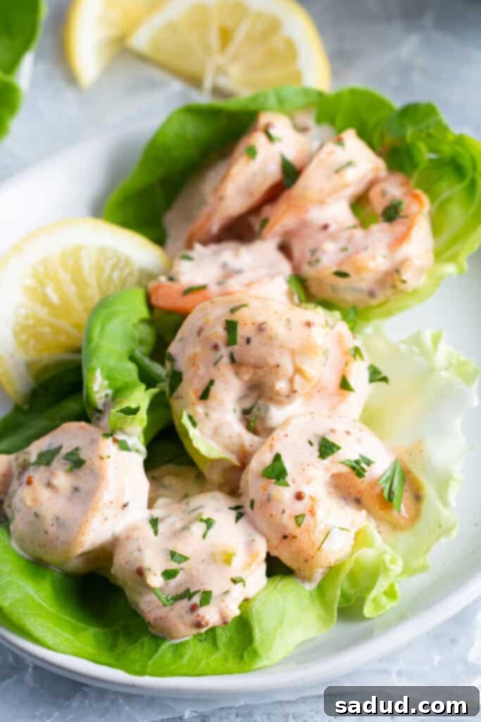 Close-up view of shrimp remoulade on a bed of lettuce with lemon wedges, showcasing the creamy sauce and succulent shrimp.