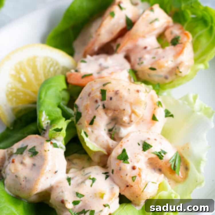 Close-up view of shrimp remoulade on a bed of lettuce with lemon wedges.