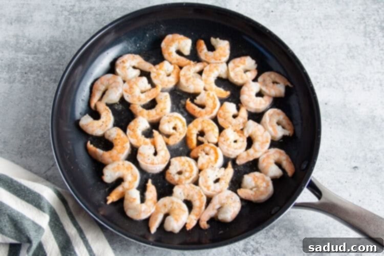 Shrimp in large cast iron skillet on grey background.