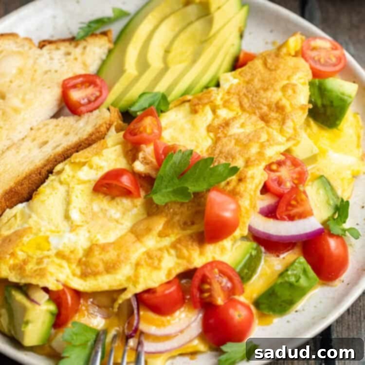 Avocado omelette on a white plate with red onion, cherry tomatoes, fresh herbs, and slices of avocado.