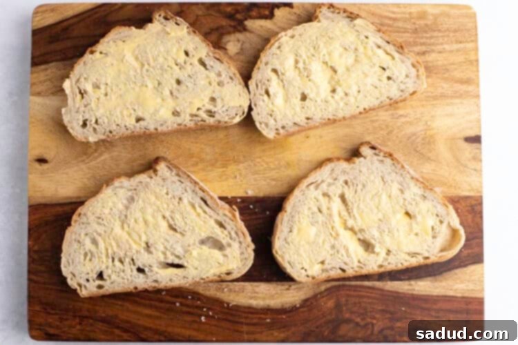 4 slices of buttered sourdough bread on a wooden cutting board.