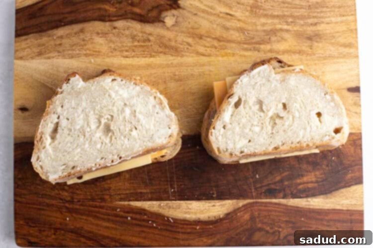 Sourdough sandwiches topped with mayonnaise on a wooden cutting board.