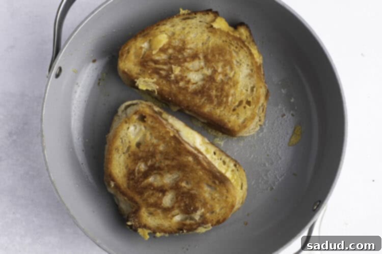 Overhead view of two sourdough grilled cheese sandwiches in a large skillet.