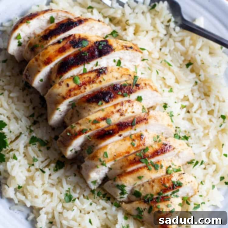 Close-up of grilled chicken on a bed of rice on a white plate, ready to serve.