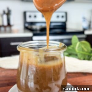 A jar of healthy homemade salted caramel sauce with a spoon, next to a caramel macchiato.